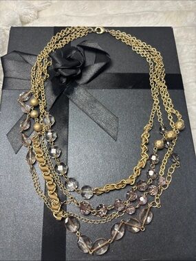 Multi strand  gold-tone necklace featuring light violet and faceted beads